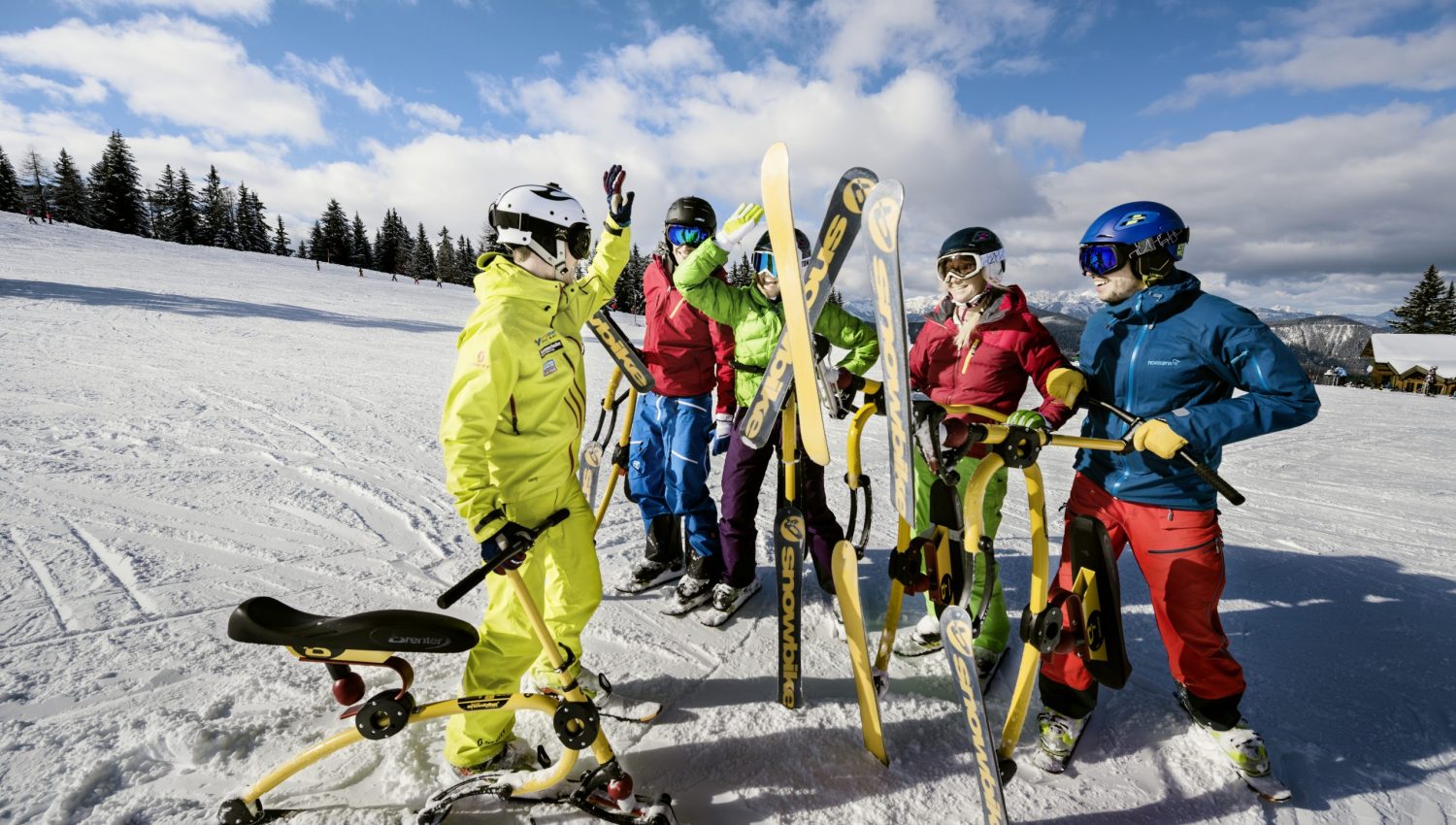 Die Piste mit dem Snowbike neu entdecken. Am Bild sieht man eine Gruppe von mehreren Personen und einen Guide mit ihren Snowbikes. Der Guide und eine Snowbikerin klatschen gerade ein.